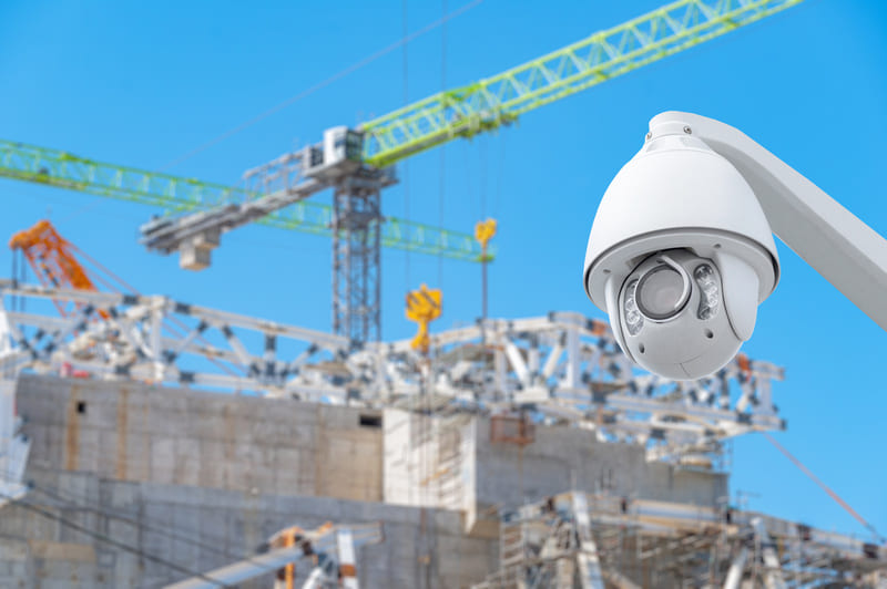 Kamera CCTV monitorująca plac budowy z widokiem na żurawie i rusztowania